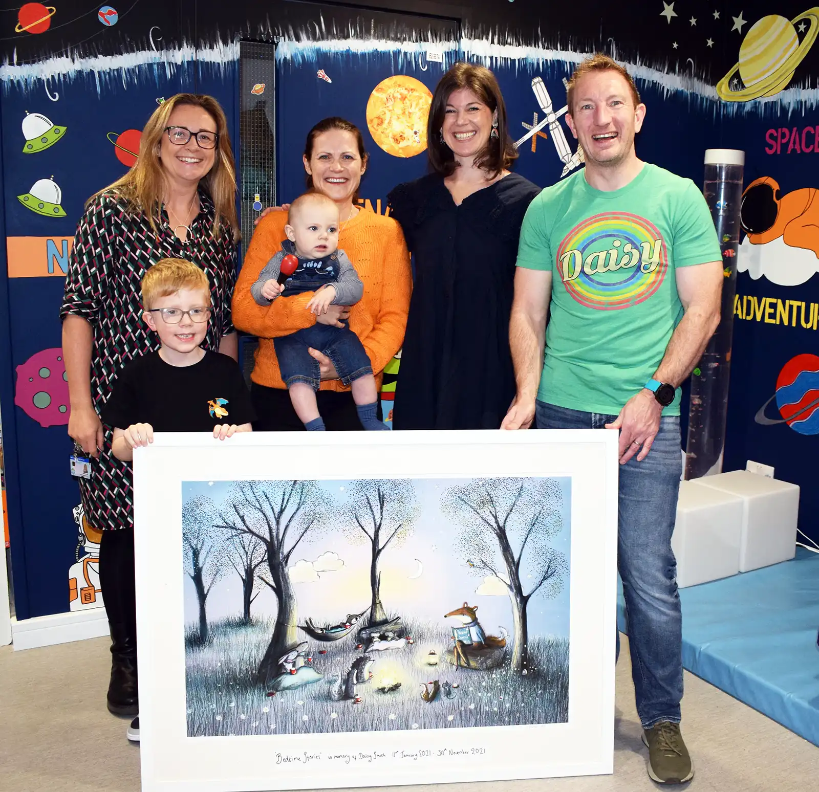 Clare Hollingsworth, Zac, Katie with baby Toby, artist Lorna and Graham with the picture Graham and Katie commissioned for Kingfisher Ward