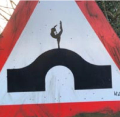 A ballerina added to a humpback bridge sign on a bridge