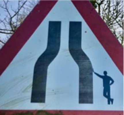 A man propped up a narrow road warning as you enter Henstridge from the east on the A30