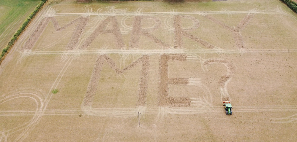 The words 'Marry Me?' written in a field of wheat